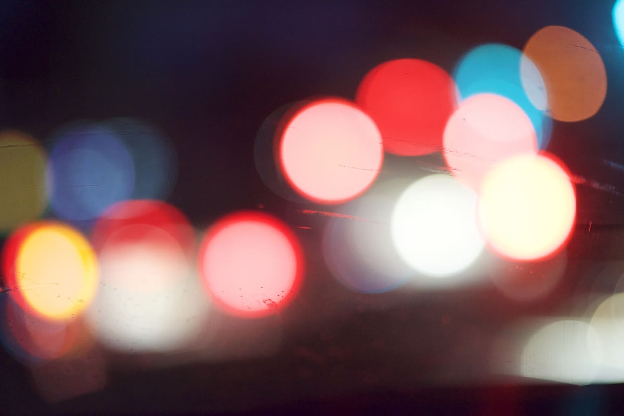 Blurred car head and tail lights seen through a windshield.